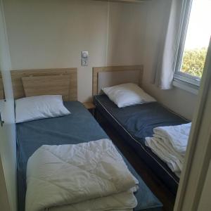 サン・ジャン・ド・モンにあるMobil-home Saint Jean de montの窓のある小さな部屋にベッドが2つある