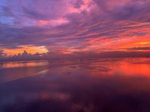 a sunset on a beach with people in the water at 175 Sqm Luxurious Modern 3 Bedrooms Facing Manila Bay Sunset, Airports, Okada, Solaire, MOA in Manila