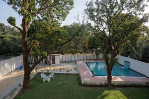 a backyard with a swimming pool and two trees at Corbett Hidden Paradise in Rāmnagar