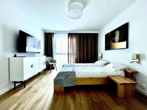 Un dormitorio con una cama, una cómoda y un televisor. en Apartamenty Karin Wladyslawowo, en Władysławowo