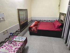 a bedroom with a red bed and a table at Aastha Krishna Homestay in Mathura +11 photos