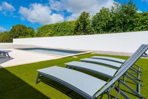 um grupo de cadeiras sentadas na relva perto de uma piscina em Villa Fifty Shades of Grey em Campelos