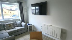 ein Wohnzimmer mit einer Couch und einem Fernseher an der Wand in der Unterkunft 5 Penhale in Perranporth