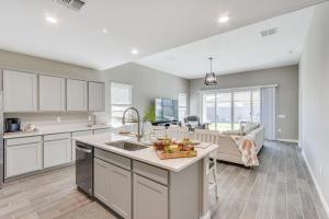 a kitchen with white cabinets and a living room at Maricopa Home with Yard - 1 Mi to Harrahs Casino! in Maricopa