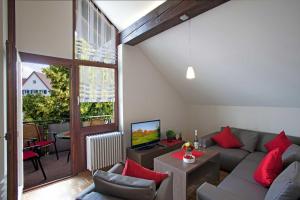 a living room with a gray couch and red pillows at Ferienwohnungen Merkle in Wasserburg am Bodensee