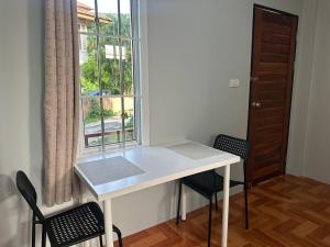 ein weißer Tisch und Stühle in einem Raum mit einem Fenster in der Unterkunft Mango Guest House Choeng Thale in Ban Thalat Choeng Thale + 13 Fotos