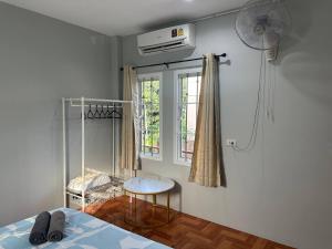 Schlafzimmer mit einem Bett, einem Fenster und einem Ventilator in der Unterkunft Mango Guest House Choeng Thale in Ban Thalat Choeng Thale