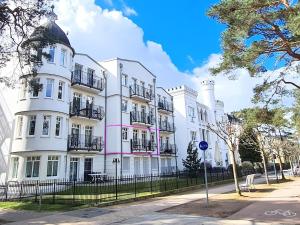 ein großes weißes Gebäude mit Balkon auf einer Straße in der Unterkunft Ferienwohnung Lieblingssuite am Strand in Ahlbeck