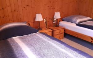 two beds in a room with two lamps on wooden walls at Ferienhaus Lerche 3 in Wulfskuhl