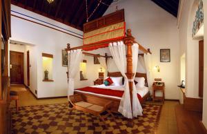 1 dormitorio con cama con dosel en una habitación en Chidambara Vilas - A Luxury Heritage Resort en Kānādukāttān