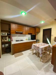 a kitchen with a table and a kitchen with wooden cabinets at Bay Mau Homestay, 2BR House with generator- near Dahican beach in Mati