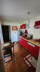 a kitchen with red cabinets and a table in it at L'Escale - private bed, shower room & kitchen in Blagnac