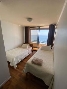 two beds in a room with a view of the ocean at Deptos en Iquique, Chile, frente a Playa Brava in Iquique