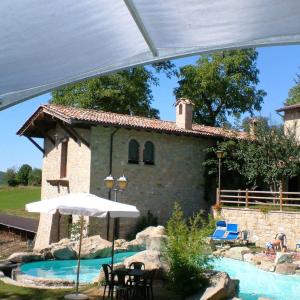 a house with a swimming pool and an umbrella at Agriturismo La Fenice in Tolè