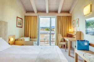 a hotel room with a bed and a desk with a view at Hotel Caesius Thermae & Spa Resort in Bardolino