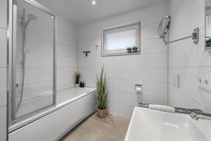a white bathroom with a tub and a sink at Ocean Star- 1 OG, Balkon, Hafenblick, Kamin in Olpenitz +33 photos