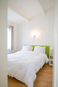 ein Schlafzimmer mit einem weißen Bett mit grünem Kopfteil in der Unterkunft jolie maison de vacances proche du lac de tanchet 6 personnes in La Pironnière