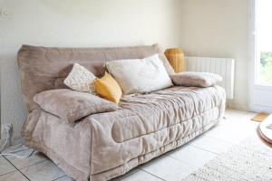 eine Couch mit Kissen darauf in einem Wohnzimmer in der Unterkunft jolie maison de vacances proche du lac de tanchet 6 personnes in La Pironnière