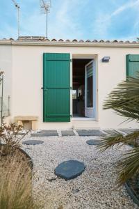 ein Haus mit grünen Türen und einem Kieshof in der Unterkunft jolie maison de vacances proche du lac de tanchet 6 personnes in La Pironnière