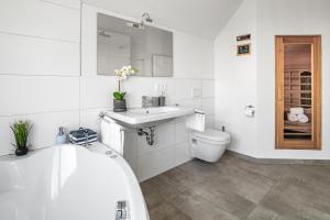 a bathroom with a tub and a sink and a toilet at SeaPearl- Hafenblick, Terrasse, Bad mit Infrarotsauna und Whirlwanne in Olpenitz +30 photos