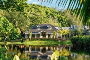 a house with a pond in front of it at Cheval Blanc Seychelles in Takamaka