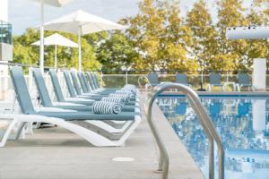 a row of lounge chairs next to a swimming pool at Aparthotel Ona Palamós in Palamós