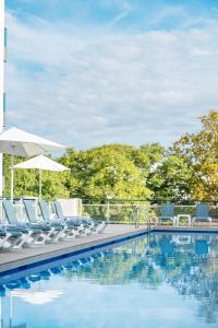 a pool with lounge chairs and an umbrella at Aparthotel Ona Palamós in Palamós