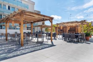 a patio with tables and chairs under a pavilion at Aparthotel Ona Palamós in Palamós