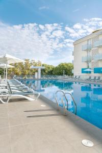 a swimming pool with chairs and a building at Aparthotel Ona Palamós in Palamós