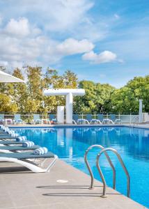 a swimming pool with lounge chairs in a resort at Aparthotel Ona Palamós in Palamós