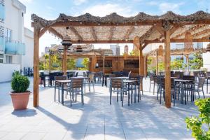 a patio with tables and chairs under a pergola at Aparthotel Ona Palamós in Palamós