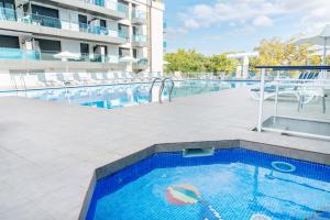 a large swimming pool with chairs and a building at Aparthotel Ona Palamós in Palamós