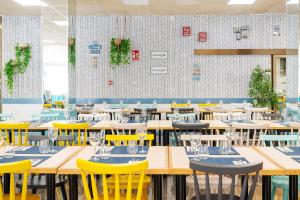 a dining room with tables and yellow chairs at Aparthotel Ona Palamós in Palamós