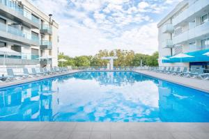 a large swimming pool in front of a building at Aparthotel Ona Palamós in Palamós