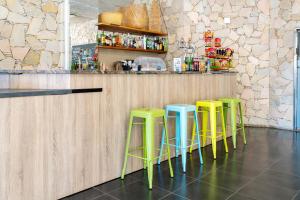 a row of green and blue stools at a bar at Aparthotel Ona Palamós in Palamós