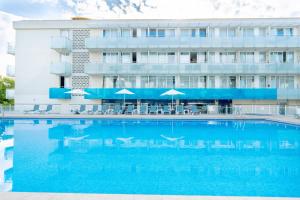a hotel with a large swimming pool in front of a building at Aparthotel Ona Palamós in Palamós