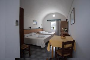 a hotel room with two beds and a table and a window at SUN -RISE in Perissa