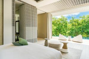a bedroom with a bed and a large window at Cheval Blanc Seychelles in Takamaka +76 photos