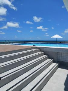 una rampa di scale che porta a una piscina con ombrellone di Flat beira mar, Olinda 4 Rodas 313 a Olinda