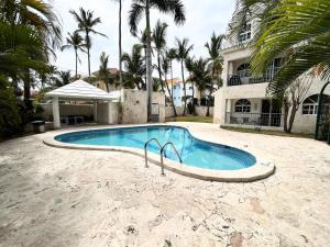 una piscina frente a una casa con palmeras en Cozy Condo - 4 min to the Beach, en Punta Cana