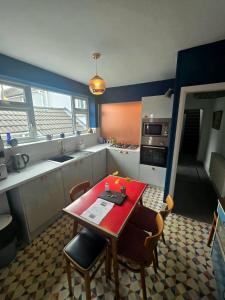 a kitchen with a red table and chairs in it at Inalong - Quirky property with sea views above an Ale House in The Mumbles +11 photos