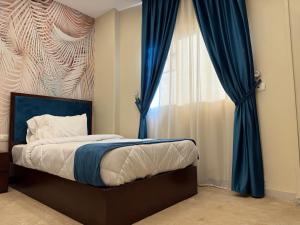 um quarto com uma cama com cortinas azuis e uma janela em Alba pyramids view em Cairo