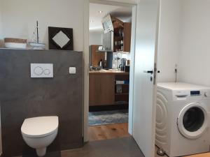 a bathroom with a toilet and a washing machine at Ferienwohnung Pölzl in Chieming +25 photos