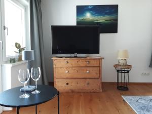 a living room with a tv and two wine glasses on a dresser at Ferienwohnung Pölzl in Chieming