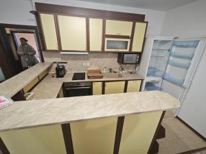 a kitchen with yellow cabinets and a sink and a refrigerator at Banchevi Guest Apartment in Haskovo