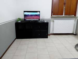 ein Wohnzimmer mit einem Fernseher auf einer schwarzen Kommode in der Unterkunft Two-room apartment in Voghera's historic center in Voghera