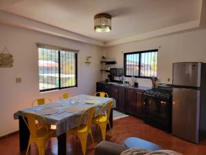 a kitchen with a table with yellow chairs and a refrigerator at Casita Central in Boquete