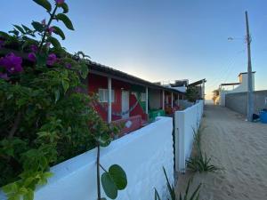 a white fence next to a house with purple flowers at Pousada Brisa do Mar in Galinhos +10 photos