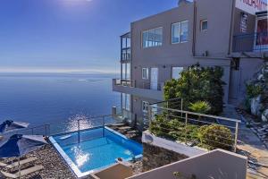 a building with a swimming pool next to the ocean at Akrotiri Panorama- luxury rental apartments with sea view in Rodakino