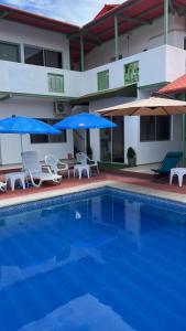 a swimming pool with chairs and umbrellas and a building at Hostal Canuto Inn in Ayangue +5 photos